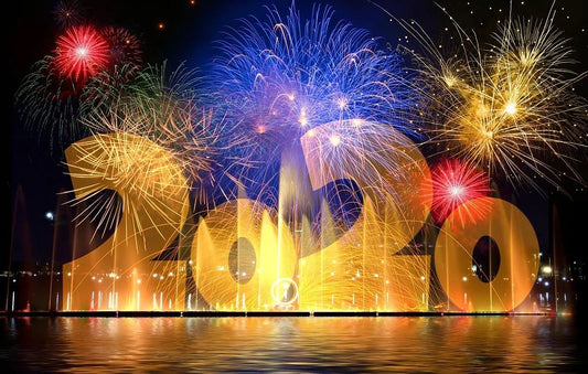 Image of colourful fireworks over water with gold 2020.