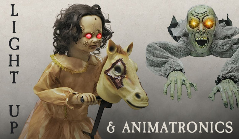 Halloween promotional graphic with the text "LIGHT UP & ANIMATRONICS." On the left, a creepy Victorian-style doll child with glowing red eyes rides a stick hobby horse with a wounded, realistic horse head. On the right, a ghastly, green-skinned zombie creature with glowing yellow eyes, an open mouth, and ragged grey robes crawls forward with hands outstretched. Click to shop all Halloween Animatronics and Light up.