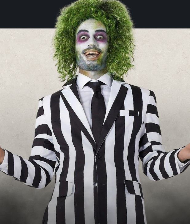 A man wearing a Beetlejuice Costume on a beige background. Click to shop all Beetlejuice Halloween Costumes. 