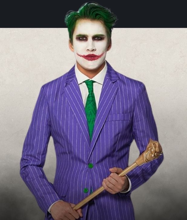 A man wearing a Joker Halloween Costume on a beige background. Click to shop all Joker Costumes. 