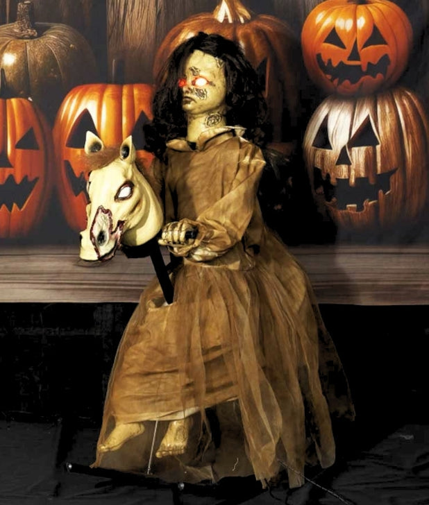 A room with a pumpkin background and an animatronic of a haunted doll on a rocking horse. Click to shop all Animatronics & Light Up