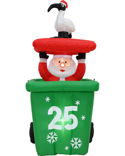 Inflatable Christmas decoration featuring Santa Claus sitting inside a green trash can with the number 25 on the front, topped with a red lid and a white flamingo figurine, isolated on a white background.