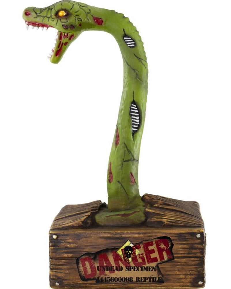 A green zombie snake animatronic decoration with a long curved neck, open mouth, red details, and a brown wood-textured base printed with a warning label reading 'DANGER UNDEAD SPECIMEN'.