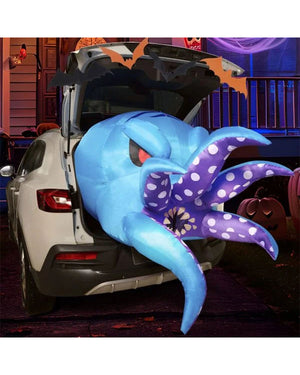 Blue and purple inflatable octopus decoration on a car trunk with Halloween decorations in the background.