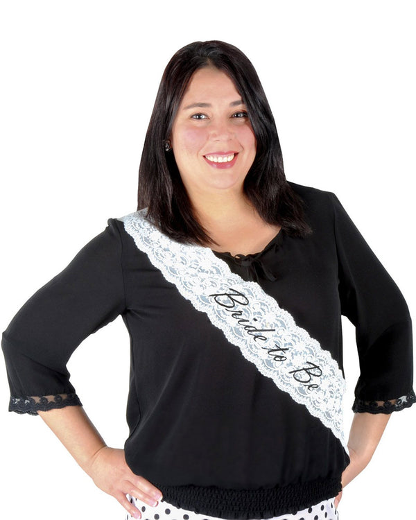 Woman wearing a black top with a 'Bride to Be' sash on a white background