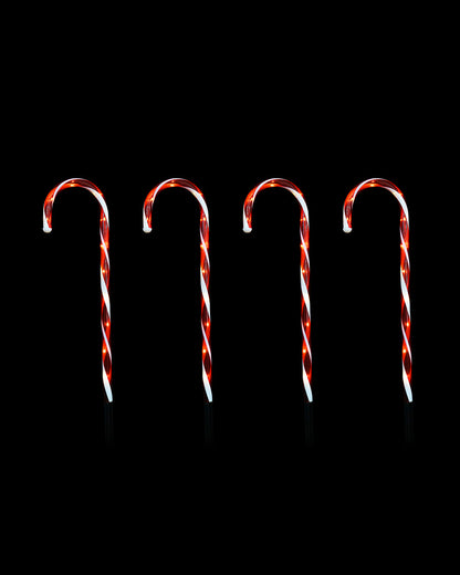 Four red and white striped candy canes arranged upright in a row against a solid black background.