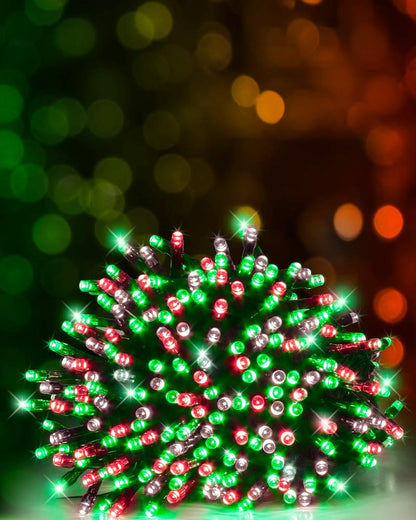 A cluster of multicolor LED holiday lights in red, green, and silver, glowing brightly against a dark background with warm bokeh lights.