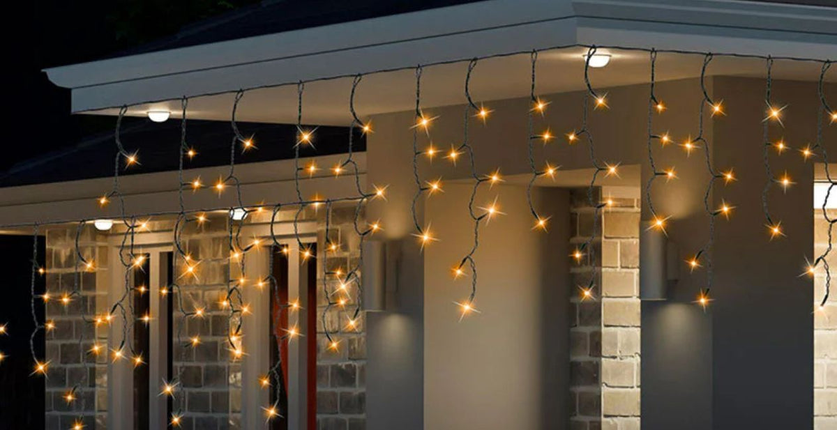 The outside of house decorated with gold sparkly Christmas lights. Click to shop all Christmas Lights.