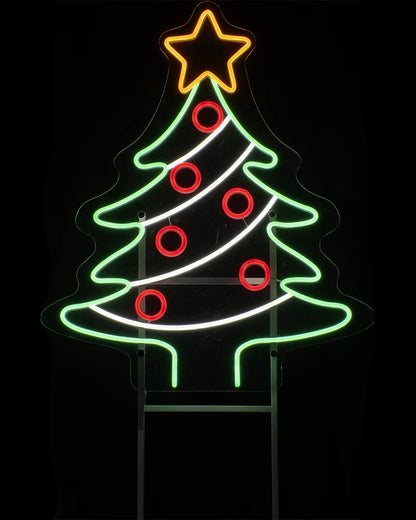 A neon Christmas tree sign with a glowing green tree outline, red circular ornaments, a yellow star topper, and white diagonal stripes, shown against a black background.