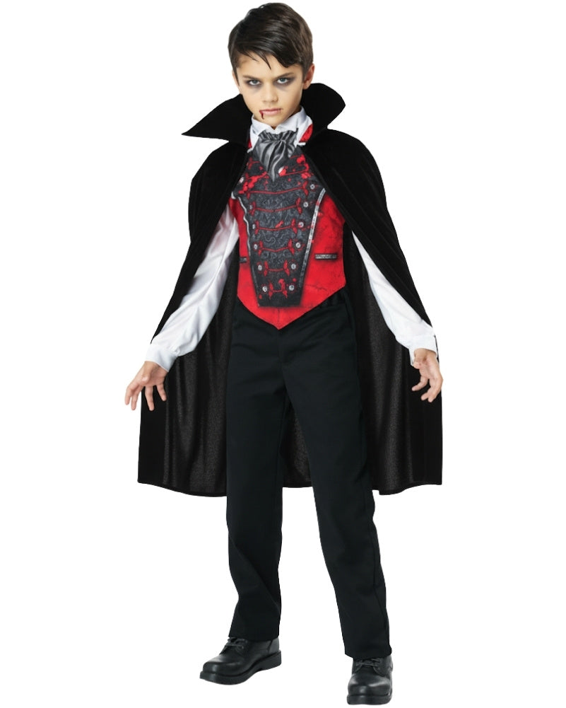Child wearing a vampire costume with a black cape, red vest, and black pants on a white background