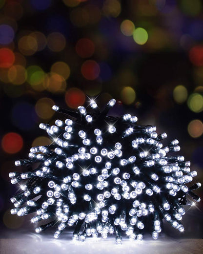 A bundle of white LED Christmas tree lights on a black wire, photographed against a dark background with colorful blurred bokeh lights.