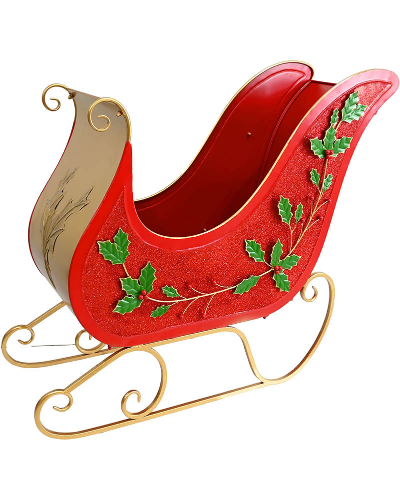 A red glittery Christmas sleigh decoration with green holly leaf accents and a gold metal frame, shown on a plain white background.