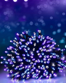 A bundle of Christmas string lights glowing with purple and blue lights, set against a dark blue bokeh background.