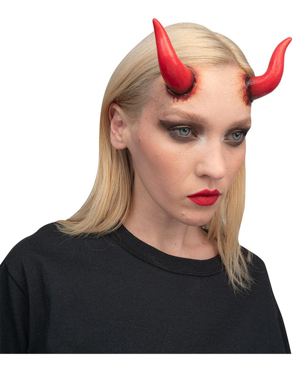 Person wearing red devil horns with a plain background