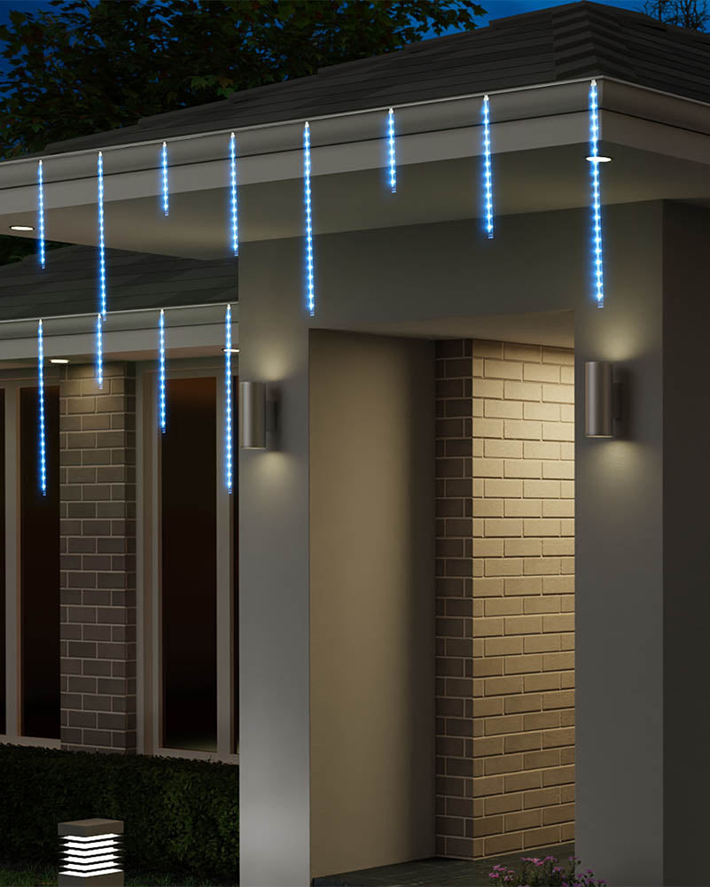 Blue LED icicle string lights hanging from the eaves of a modern house at night, illuminating the entryway and brick columns.