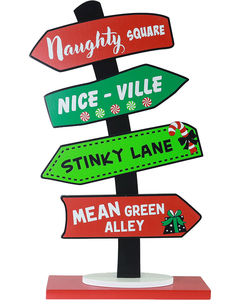 A Christmas-themed directional signpost with four arrow-shaped signs pointing to 'Naughty Square', 'Nice - Ville', 'Stinky Lane', and 'Mean Green Alley' on a black pole with a red and white base, shown on a white background.