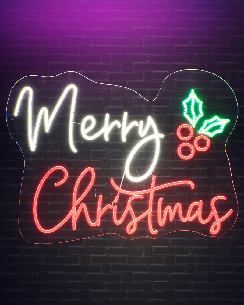 A glowing Christmas neon sign on a dark brick wall, with the words “Merry Christmas” in white and red script and a green holly leaf and berry accent.