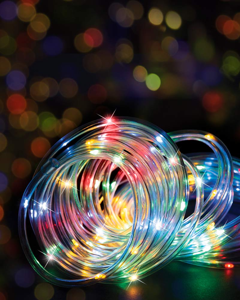 Coiled multicolor LED string lights with thin transparent wires and glowing bulbs in red, green, blue, yellow, and white, set against a dark background with colorful bokeh lights.