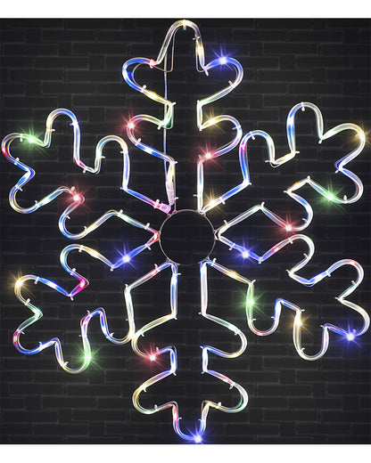 A large snowflake-shaped LED light decoration with multicolored glowing lights, shown against a dark brick wall background.