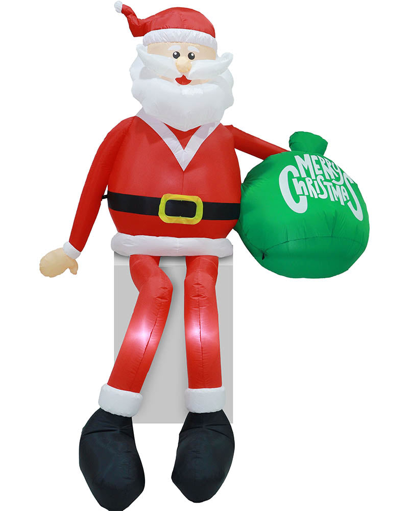 Inflatable Santa Claus figure sitting on a white block, holding a green sack that says 'Merry Christmas' in white text, isolated on a white background.