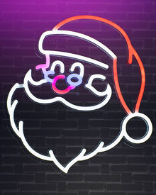 A neon sign depicting a stylized Santa Claus face and hat, glowing with white, pink, purple, and orange light against a dark brick wall background.