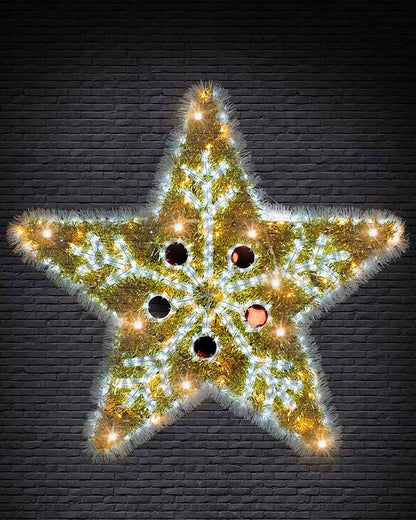 A five-pointed star-shaped Christmas decoration made of green pine branches, illuminated with warm yellow and cool white lights, set against a dark gray brick wall.