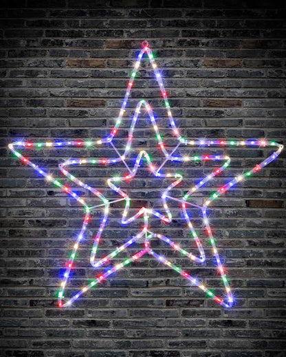 A large five-pointed star-shaped Christmas light decoration made of multicolor LED wire lights, glowing against a dark brick wall background.