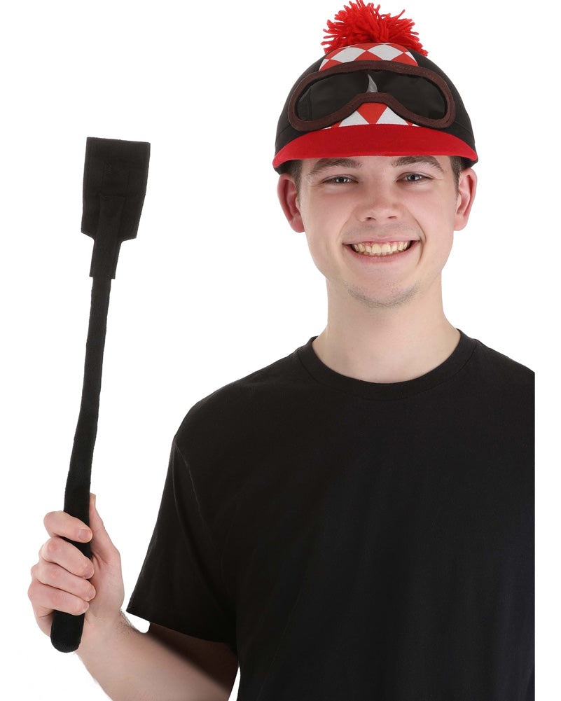 A person holding a black crop and wearing a jockey-style hat with a red pompom and goggles